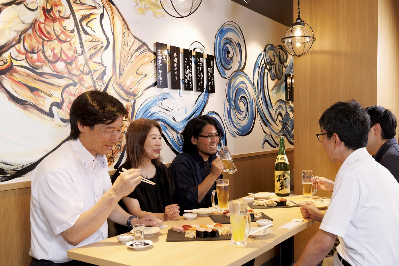 壁画に囲まれた店内で料理を囲み語らうお客様