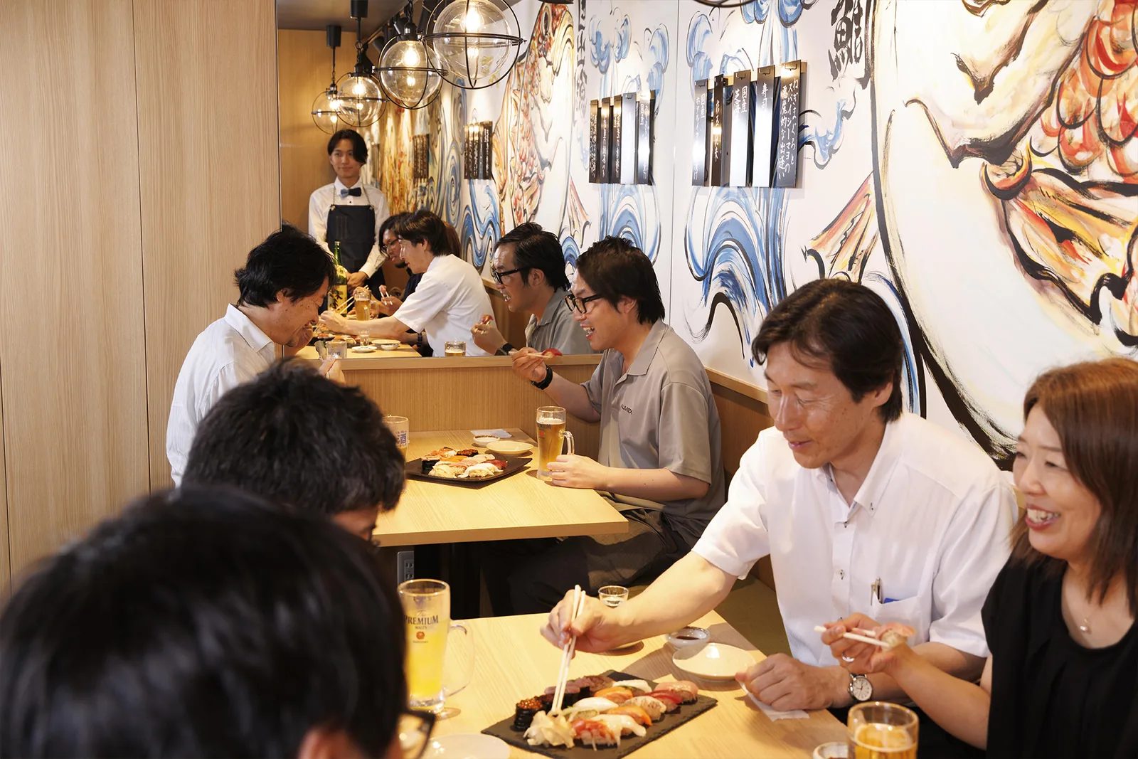 壁画の前のテーブル席で乾杯するお客様